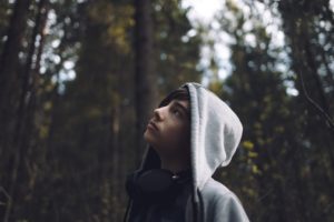 Man in hoodie looking at treees.