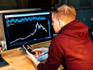 Man looks at graphs on computer screen