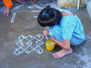 Child in India drawing a kolam floor painting 