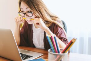 Woman biting her pencil at work